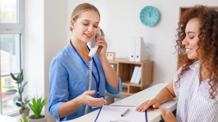 Hospital lobby receptionist scheduling a patient